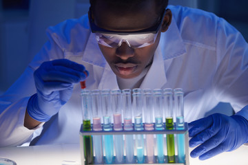 Horizontal medium close up portrait of young male medical scientist sitting at desk in modern...