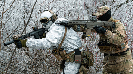 Two men in camouflage white, green uniform with machineguns. Soldiers with muchineguns go one after...