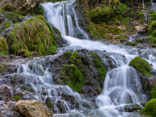 A stream of water flowing over rocks and creating a waterfall effect.