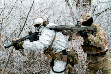 Two men in camouflage white, green uniform with machineguns. Soldiers with muchineguns go one after...