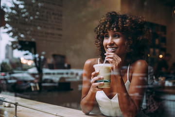 Beautful woman having a drink inside a cafe, view through the screen