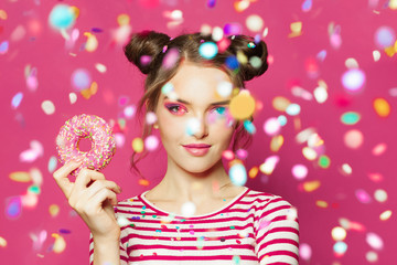 Fashion model woman with sweet donut in colorful confetti rain