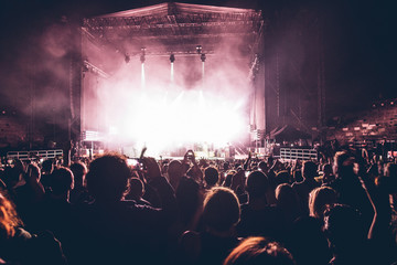 people silhouettes at the music concert. Crowd and fans showing love for the rock band at the...