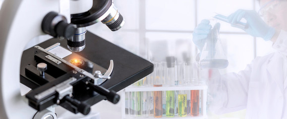 Laboratory concept; close up of microscope with a blurred picture of the scientist is researching in laboratory