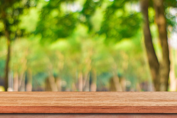 Empty wood table for product display over blur green tree garden. Blurred of nature outdoor with bokeh light background.