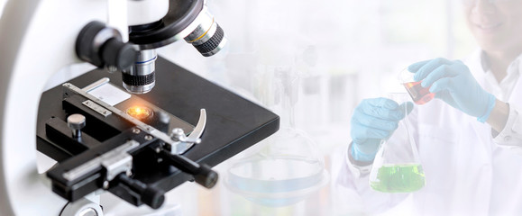Laboratory concept; close up of microscope with a blurred picture of the scientist is researching in laboratory