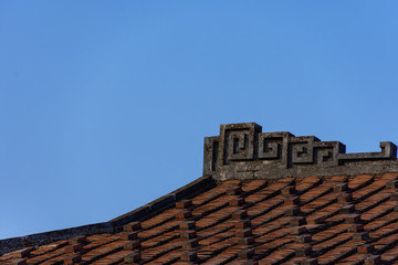 Under the blue sky, the roofs of traditional buildings are covered with red tiles, and the eaves and corners are painted with stripes