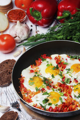 Shakshouka with five cooked eggs on top of tomato sauce in cast iron skillet	
