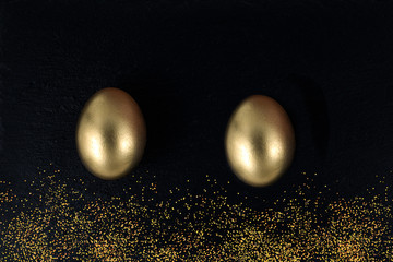 Minimal gold eggs easter concept. Golden eggs with golden shine decorated confetti for banner, greeting card, social media advertise on black stone. Flat lay trendy easter greeting card copy space
