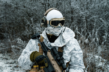 Closeup military man in white camouflage uniform with machinegun