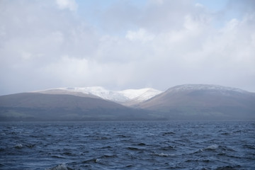 Calm peaceful atmospheric view of lake at Loch Lomond during storm cloud weather from rain to sunshine