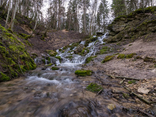 A stream of water flowing over rocks and creating a waterfall effect.