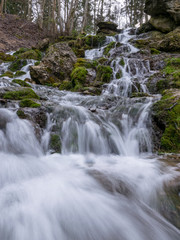 A stream of water flowing over rocks and creating a waterfall effect.