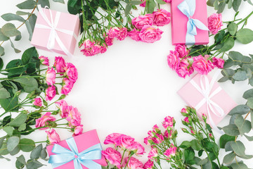 Floral frame of pink roses flowers and gifts on white background. Flat lay, Top view.