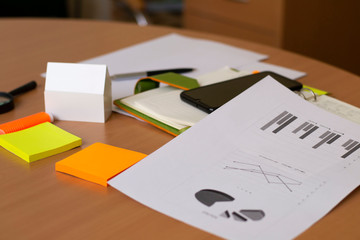 business life concept on the table lies smartphone paper notebook paper with white model of the house.