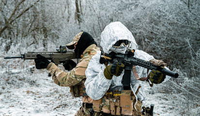Two men in camouflage white, green uniform with machineguns back to back. Soldiers with muchinegun...