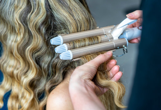 Blonde Frau in der Maske einer B&uuml;hne (Theater) bei Hair-Stylistin mit Lockenstab
