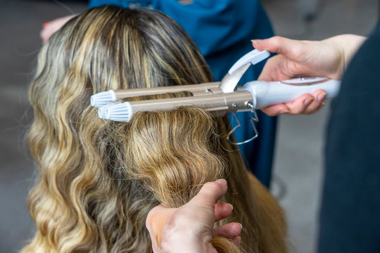 Blonde Frau in der Maske einer B&uuml;hne (Theater) bei Hair-Stylistin mit Lockenstab