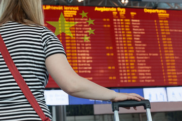 Fototapeta na wymiar Woman looks at the scoreboard at the airport. Select a country China for travel or migration.
