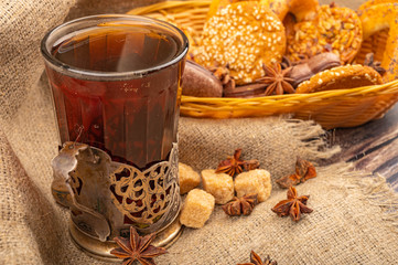 A glass of tea in a vintage Cup holder and cookies in a wicker basket on a background of rough homespun fabric. Close up.
