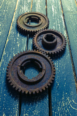 Old rusty gears from machines on a wooden table.