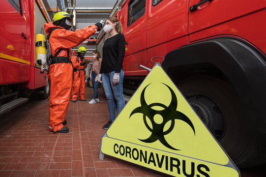 Corona Virus Pandemie ist ausgebrochen. Feuerwehrleute in Seuchenschutzausrüstung und medizinische Helfer messen Fieber bei Personen, um die Epedemie einzudämmen 