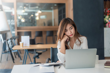 Young asian businesswoman are tired and not happy working with a laptop computer in the office