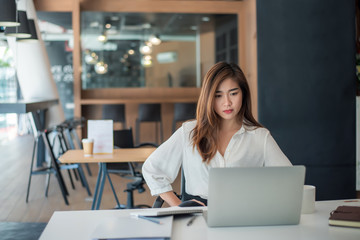 Young asian businesswoman are tired and not happy working with a laptop computer in the office