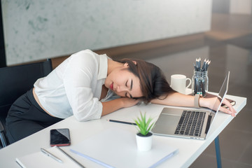 Tired businesswoman sleeping on the desk in the office. Overworked concept. © amnaj