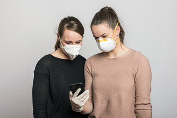 Frauen mit Mundschutz Maske und Schutzandschuhen tippen auf dem Mobiltelefon, machen Selfies und...