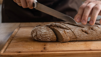 Caucasian cuts bread on a wooden board