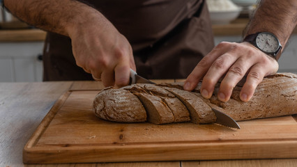 Caucasian cuts bread on a wooden board