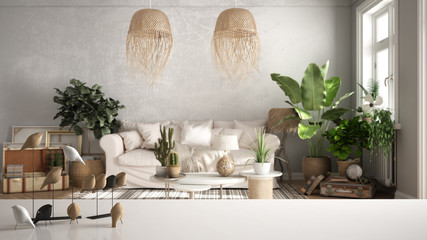 White table top or shelf with minimalistic bird ornament, birdie knick - knack over blurred vintage living room with sofa, lounge, carpet, potted plants, retro interior design