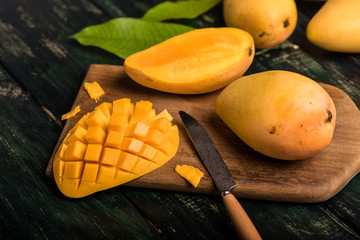 Mango on the wooden table, with cut pieces and complete