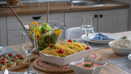 Bolognese with salad, avocado bruschetta and sauce on the table with glasses in background