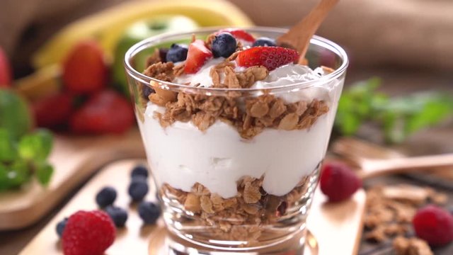 Scooping Yogurt with granola and fruits .