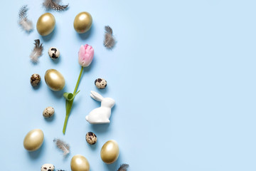 Easter frame of bunny, golden eggs, pink tulip on blue. Top view. Happy holiday.