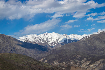 Mountain landscape. Mountain range, in the background the snow-capped peaks of the mountains, blue sky with white clouds.