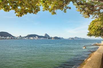 Trees and sunny day on vacation trip to the end of Copacabana beach in Guanabara Bay and in the background the Pao de Acucar mountain, in Rio de Janeiro Brazil