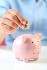 Little boy putting a coin into piggy bank for saving 