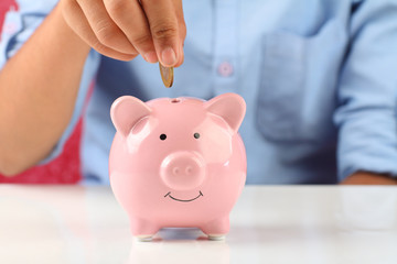 Little boy putting a coin into piggy bank for saving	
