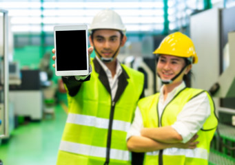 Businessmen or male engineers and female engineers are working in industrial plants that have machines and injection molds, with tablets used to control technology.