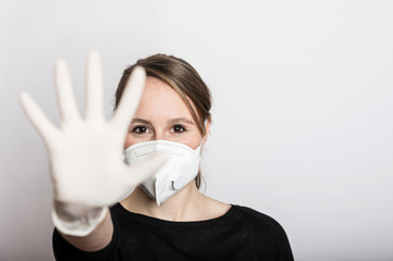 Frau mit Mundschutz und Handschuhe stoppt die Corona Virus Pandemie