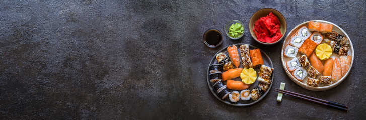 Fototapeta na wymiar sushi rolls with rice and fish, soy sauce on a dark stone background