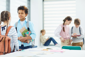 Horizontal shot of five young middle schoolers hanging out during break at school, copy space