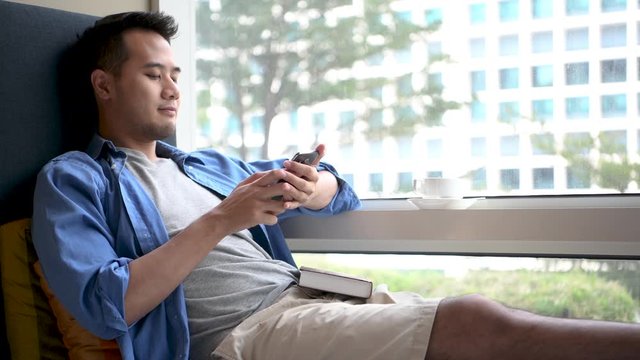 Young man using smartphone  while sitting on sofa at home .