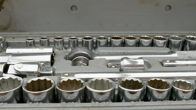 Dolly shot of a man&rsquo;s hands choosing a chrome steel socket from a set, and attaching it to the ratchet too, ready to usel.
