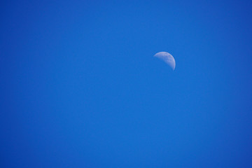 Crescent moon in a clear blue afternoon sky