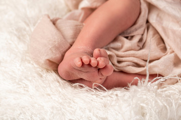 Obraz na płótnie Canvas Newborn baby on a white blanket. tiny baby feet closeup. concept of happiness. place under the text