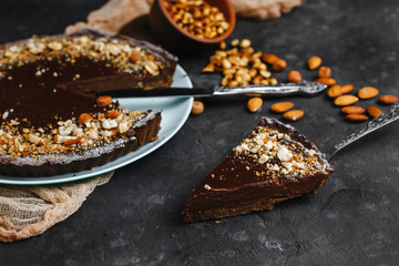 Chocolate cake, chocolate cake, dessert with nuts. a cut piece. Roasted peanuts, almonds and hazelnuts. On dark background. The view from the top. The view from the side. Space for text.